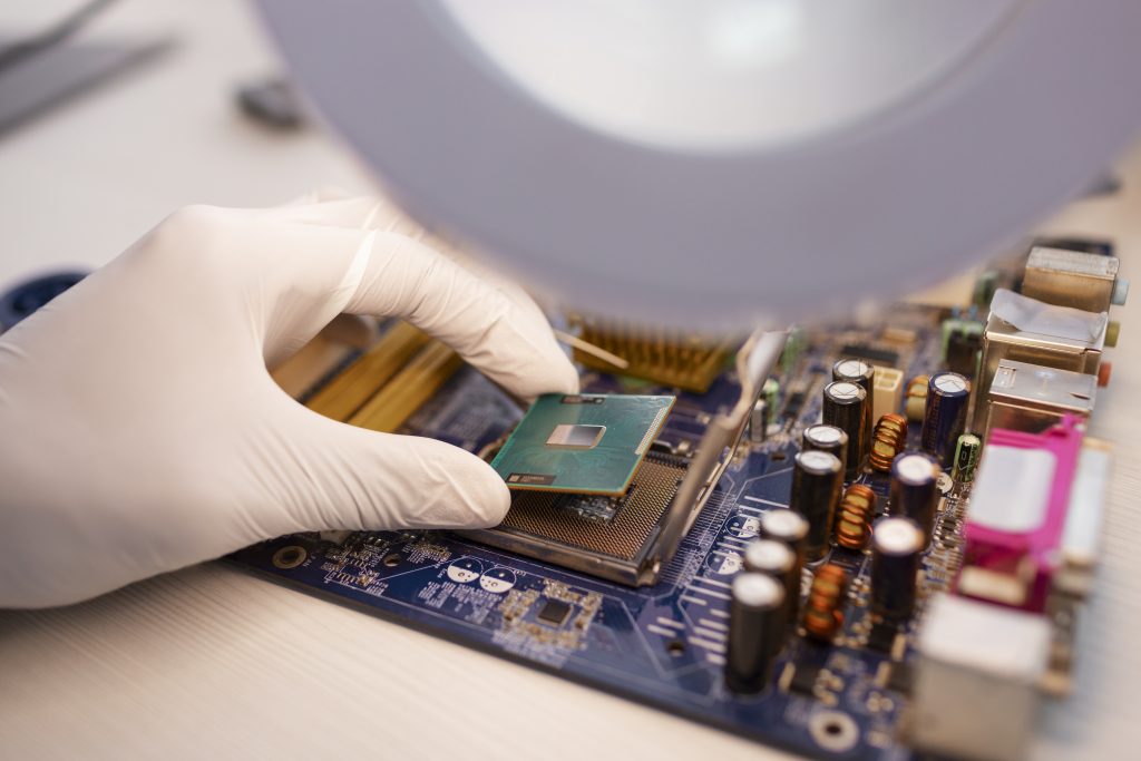 Uma mão com luva descartável instala ou remove um processador em uma placa-mãe de computador
